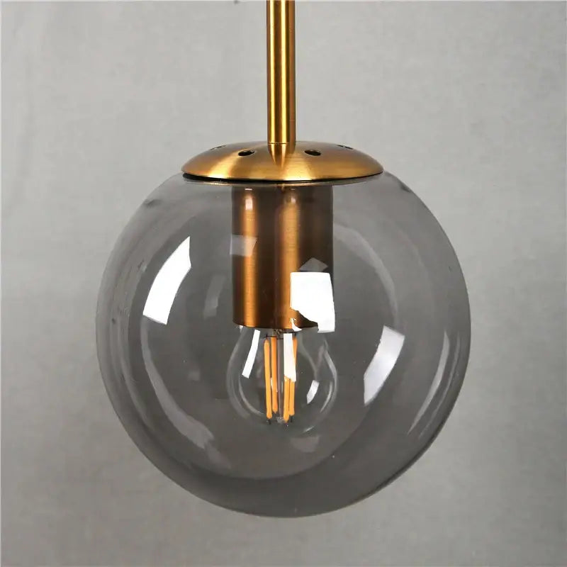 Modern brass glass ball wall lamp featuring a translucent gray glass globe with exposed led filament bulb for bedroom decorbites glass ball lighting
