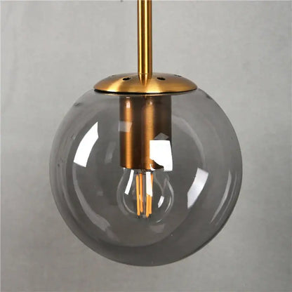 Modern brass glass ball wall lamp featuring a translucent gray glass globe with exposed led filament bulb for bedroom decorbites glass ball lighting