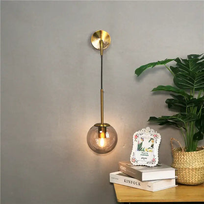 A modern brass wall lamp with a spherical smoked glass shade perfect for decorbites glass ball wall lighting