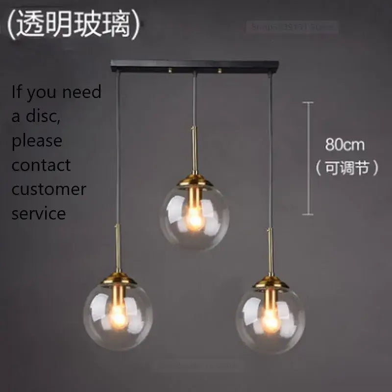 Modern brass glass ball wall lamps featuring three clear glass globe shades and brass fixtures on a black bar