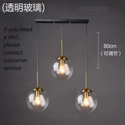 Modern brass glass ball wall lamps featuring three clear glass globe shades and brass fixtures on a black bar