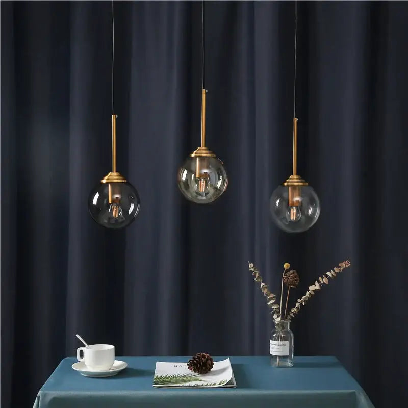 Three modern pendant lights with brass-finished stems and clear glass globe shades for decorbites glass ball wall lamps