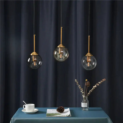 Three modern pendant lights with brass-finished stems and clear glass globe shades for decorbites glass ball wall lamps