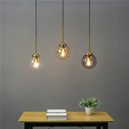 Modern brass glass ball wall lamps with clear amber and smoky glass shades hanging above a wooden table decorbites glass ball
