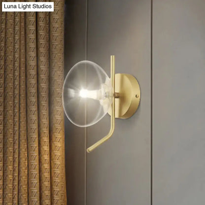 Modern brass glass dome wall sconce with a clear glass dome and gold arm for bedroom lighting