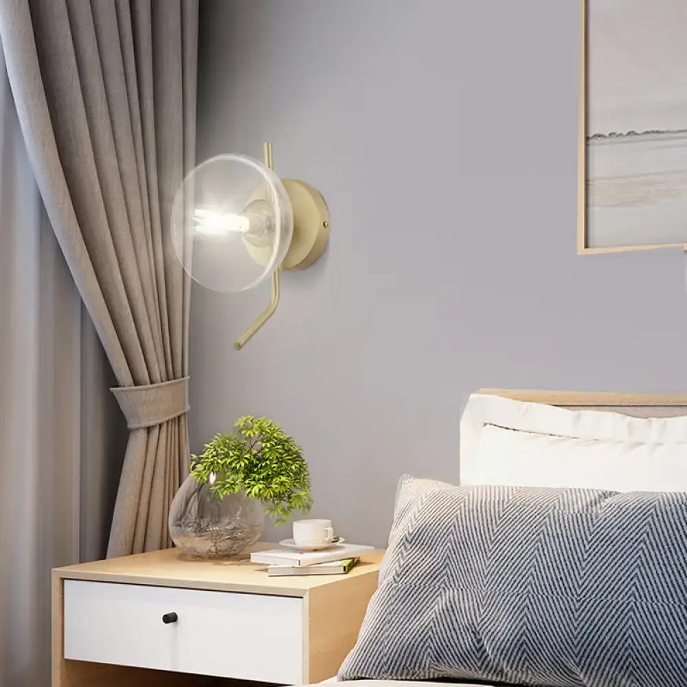 Modern brass glass dome wall sconce with gold arm and clear glass dome shade for bedroom lighting