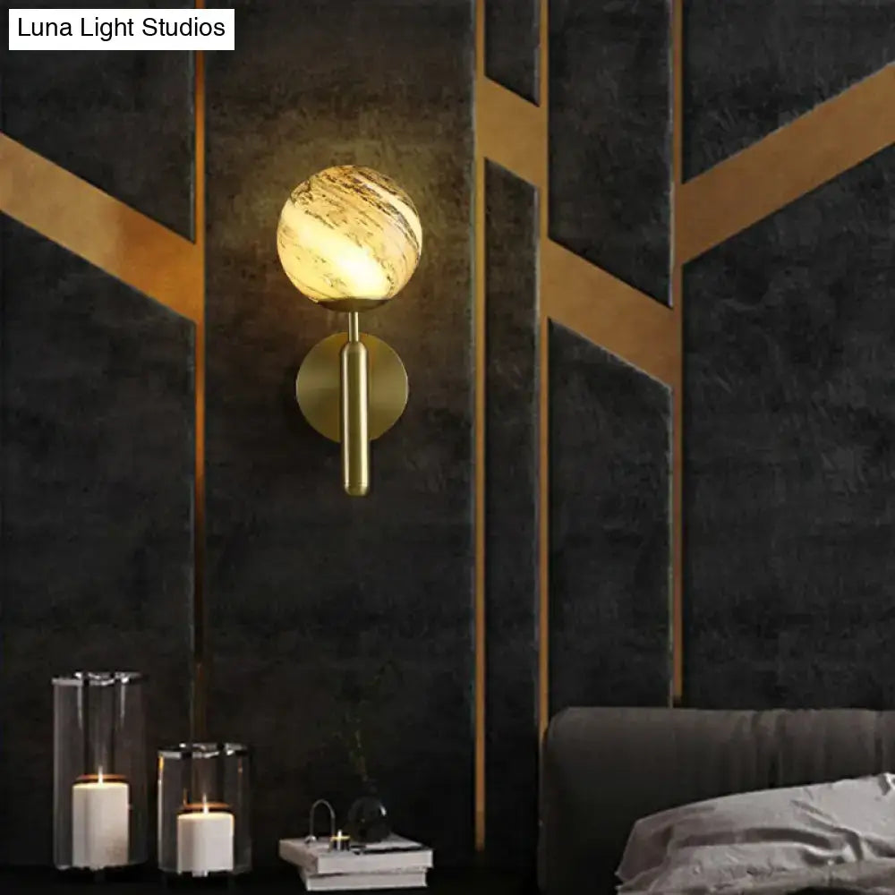 Modern brass wall mount light with gold-toned spherical marbled glass shade for living room sconce lighting