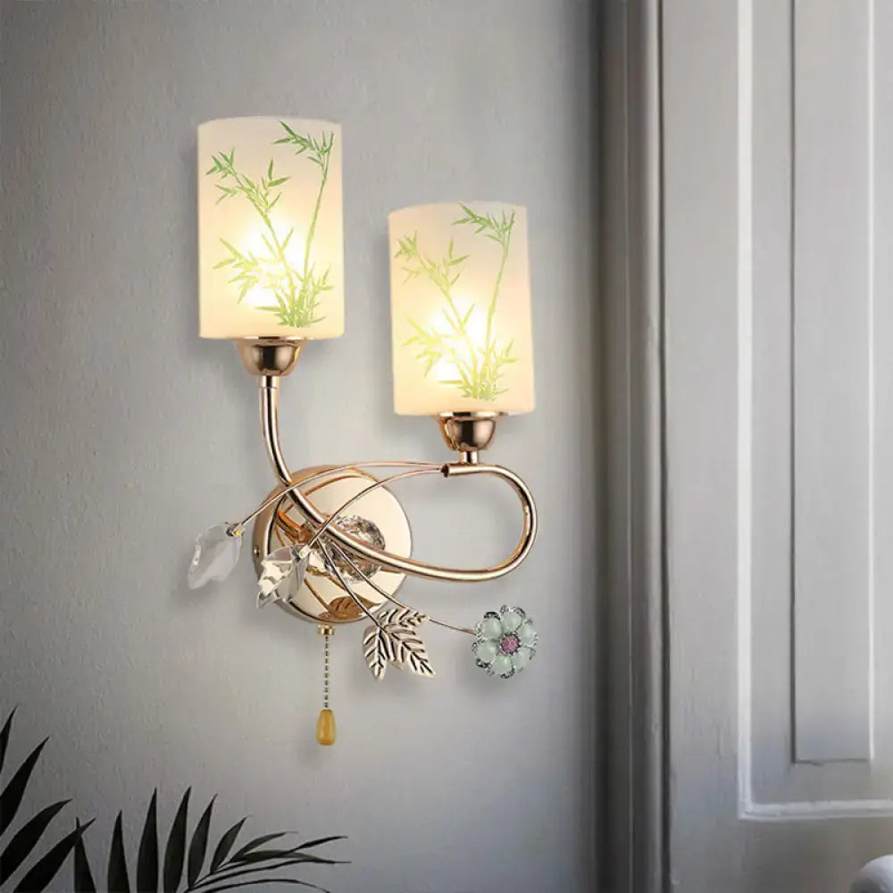 Modern brass wall lamp with glass shade and pull chain featuring frosted bamboo decals and crystal leaf accents