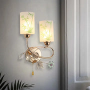 Modern brass wall lamp with glass shade and pull chain featuring frosted bamboo decals and crystal leaf accents