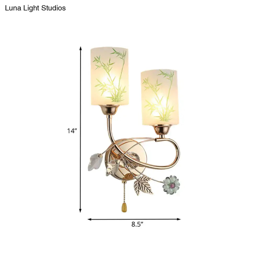 Modern brass wall lamp with glass shade, green bamboo leaf design, decorative metal accents, and pull chain for bedroom
