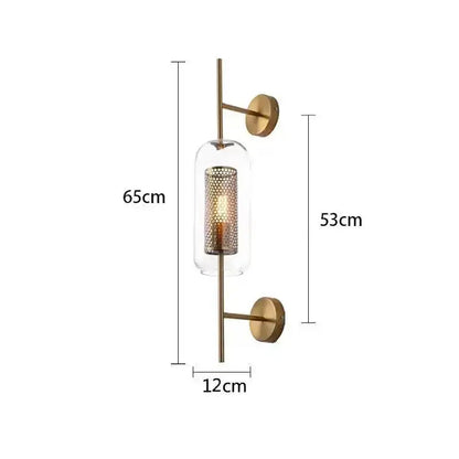 Modern brass glass wall lamp with a brass-finished sconce, clear glass cylinder, and perforated gold mesh shade for bedroom decorbites