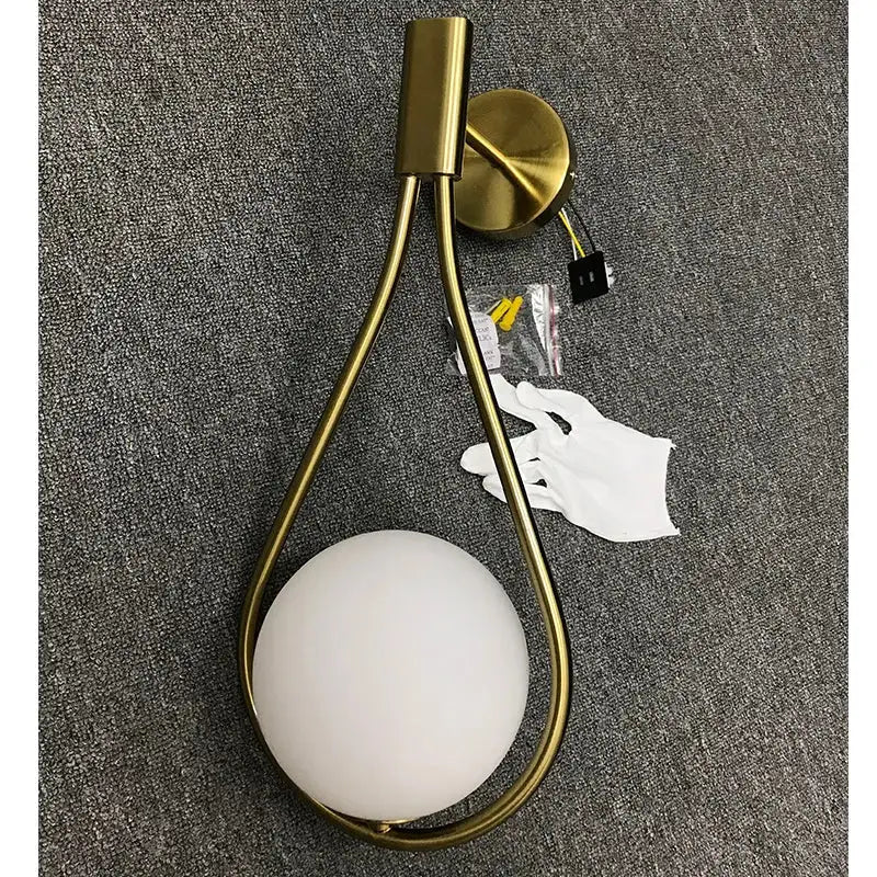 Modern brass glass wall lamp with a gold-toned teardrop frame and frosted white glass shade for bedroom lighting decorbites brass glass