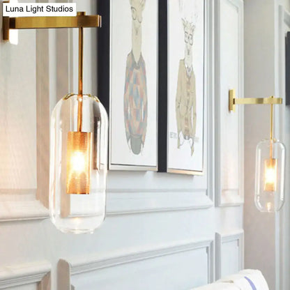 Modern brass glass wall sconce with gold-toned wire mesh guard and clear enclosure housing an illuminated bulb 110v-120v