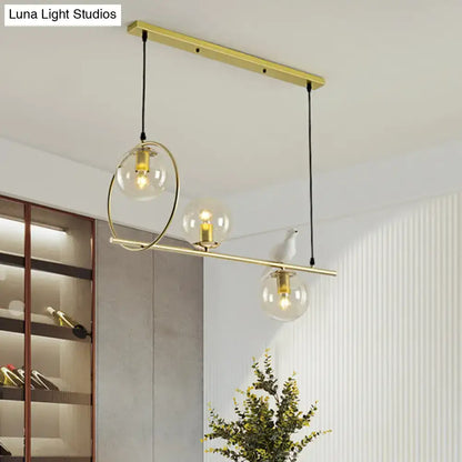 Modern brass global island lamp with gold-toned pendant light and clear glass globes suspended by black cords