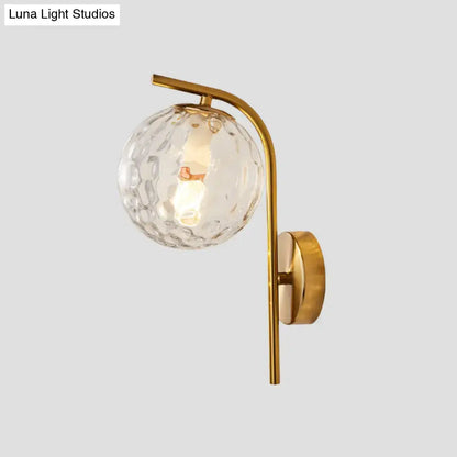 Modern brass bedside lamp with gold-toned wall sconce and textured clear glass globe inch fixture for bedroom use
