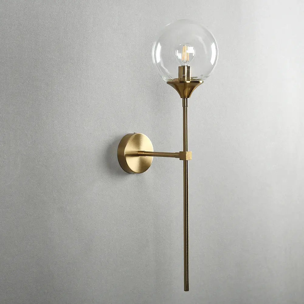 Modern brass golden glass wall sconces featuring a brass-finished sconce with a clear glass globe and exposed filament bulb