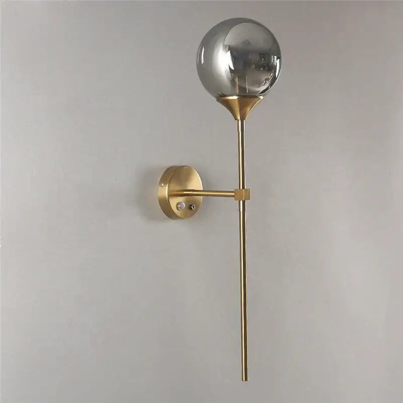 Modern brass golden glass wall sconces featuring a gold-toned frame with a spherical smoked glass globe for bedroom decorbites