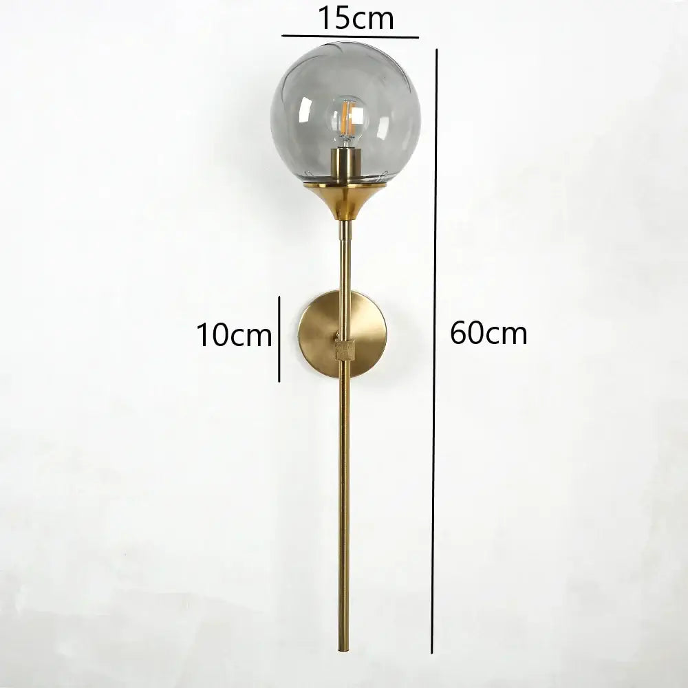 A modern brass golden glass wall sconce with a spherical smoked glass shade and exposed filament bulb for bedroom decorbites golden glass