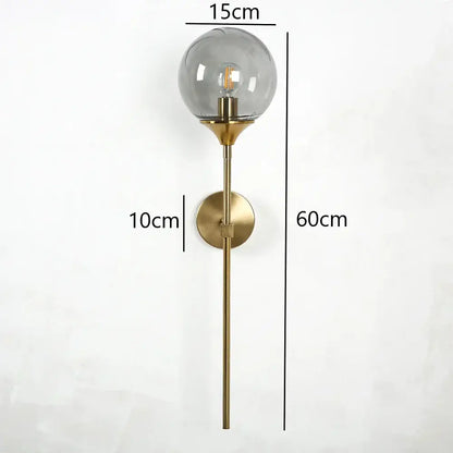 A modern brass golden glass wall sconce with a spherical smoked glass shade and exposed filament bulb for bedroom decorbites golden glass
