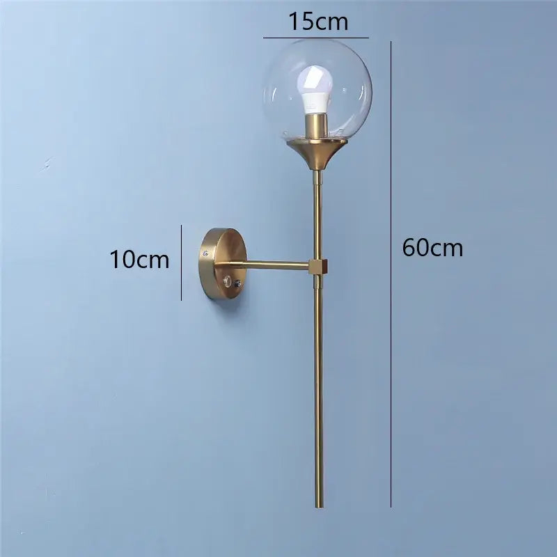 A modern brass golden glass wall sconce with clear globe and exposed bulb measuring 60cm by 15cm by decorbites golden glass