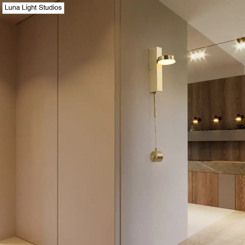 Modern brass l-shaped wall sconce with pull chain featuring a rectangular body and circular light fixture for living room