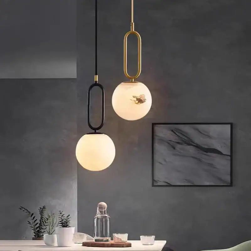 Modern brass led pendant lights with spherical frosted glass shades and gold and black decorbites brass led frames