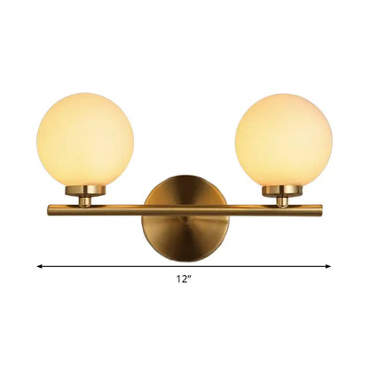 Modern brass light fixture bedroom sconce with two frosted glass globe product shades and brass-finished metal frame