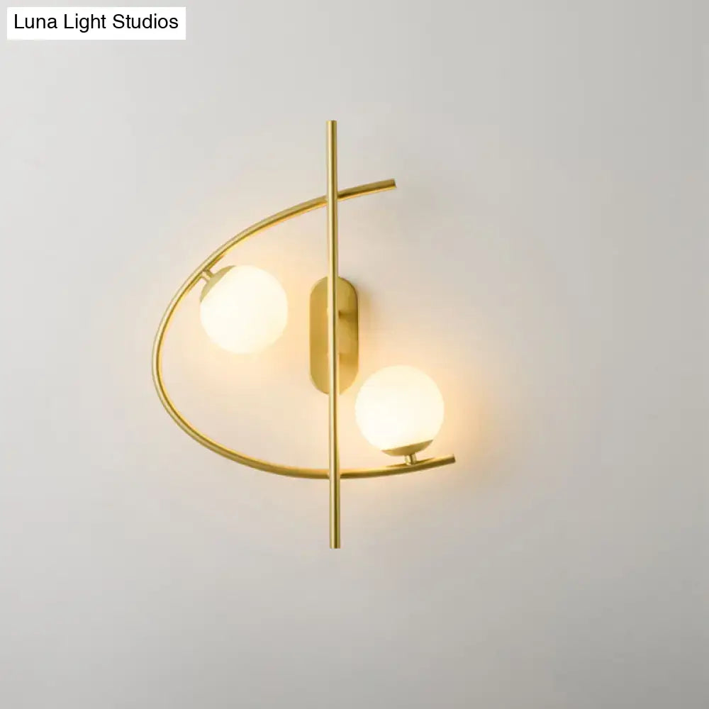 Modern brass wall sconce with milk glass ball bulbs and curved gold-toned arms for living room lighting