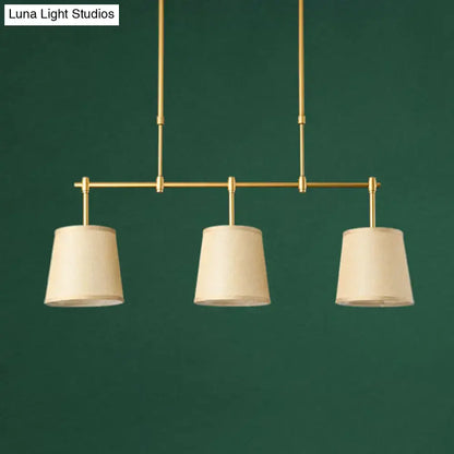 Modern brass pendant light with three off-white white green flaxen fabric shades suitable for dining room use