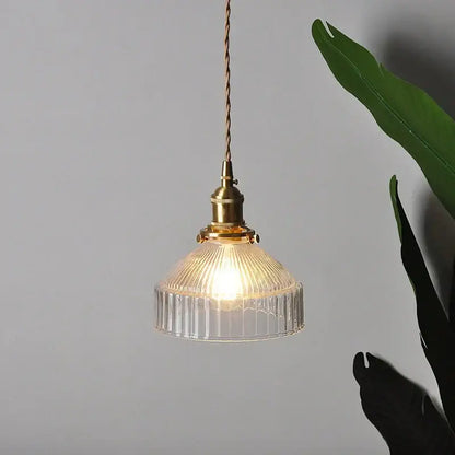 A warm-toned modern brass ribbed clear glass pendant lamp featuring a vintage-style design for dining room decorbites clear glass