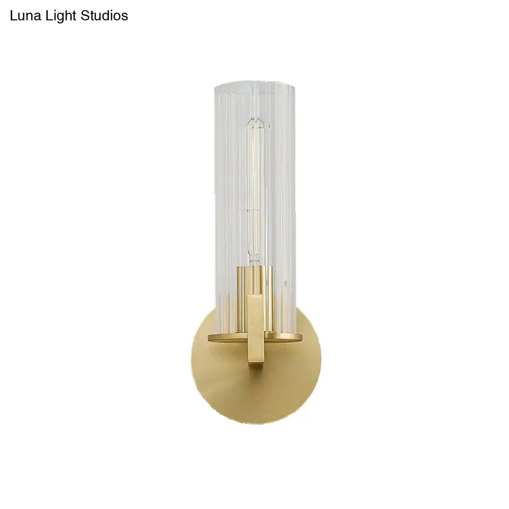 Modern brass wall sconce with a cream glass cylindrical shade and gold-toned metal base for bedroom lighting