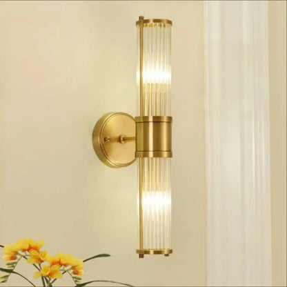 Modern brass ridged crystal wall light with brass finish and vertical glass rods emitting warm light fixture height