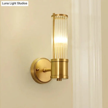 Modern brass ridged crystal wall light with gold-toned cylindrical glass shade and brushed brass finish fixture height visible