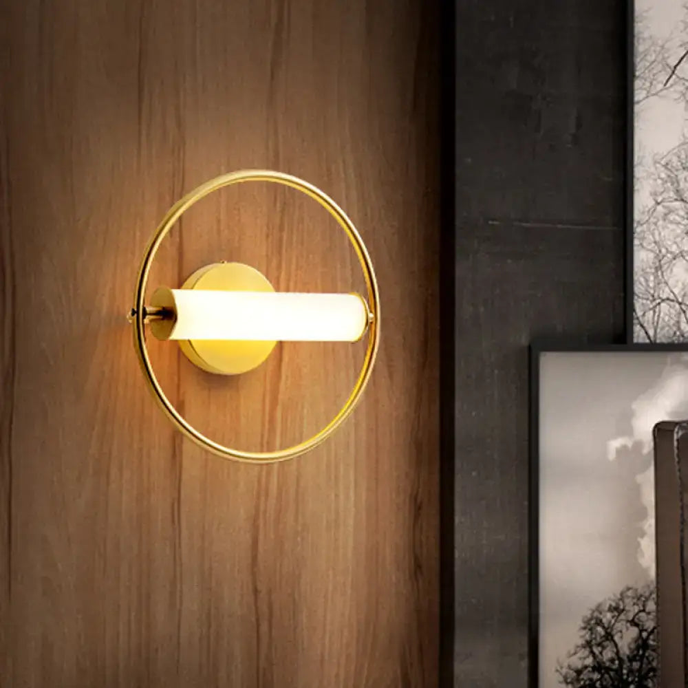 Modern brass ring wall sconce with gold-toned finish and opal glass shade featuring a sleek cylindrical light fixture