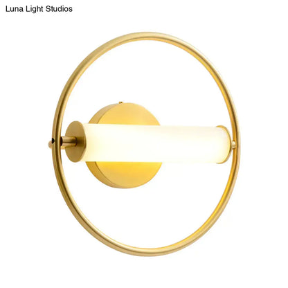 Modern brass ring wall sconce with gold-toned finish and illuminated opal glass shade for bedroom lighting