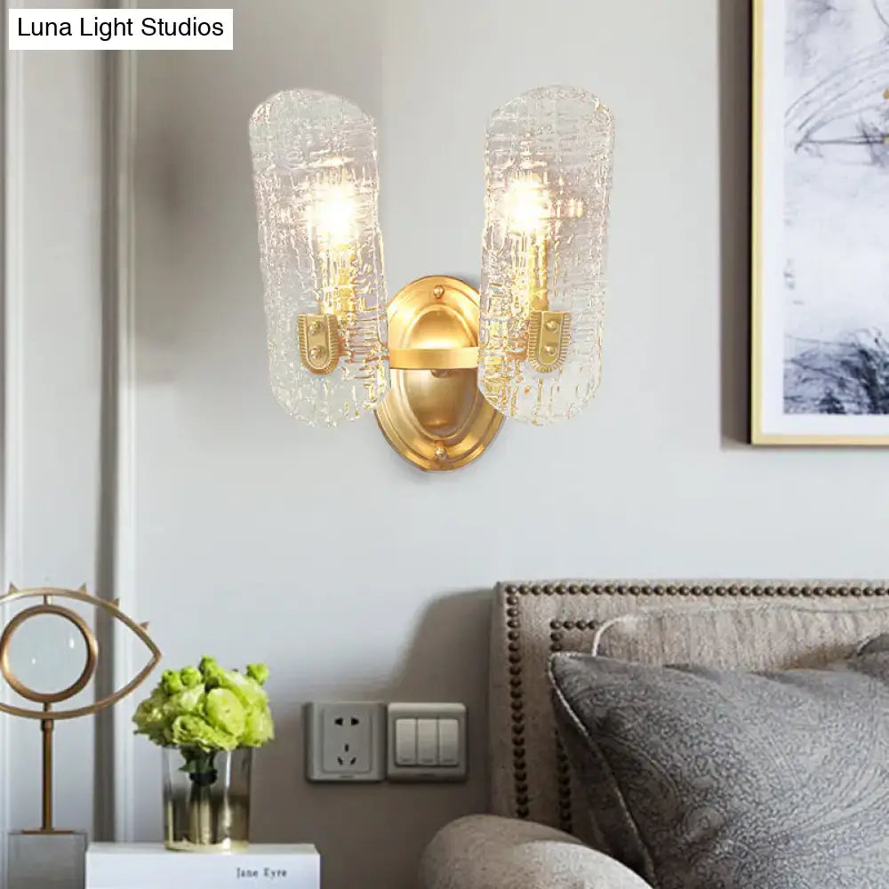 Modern brass sconce with two lights featuring gold-toned metal and clear water glass shades for living room use