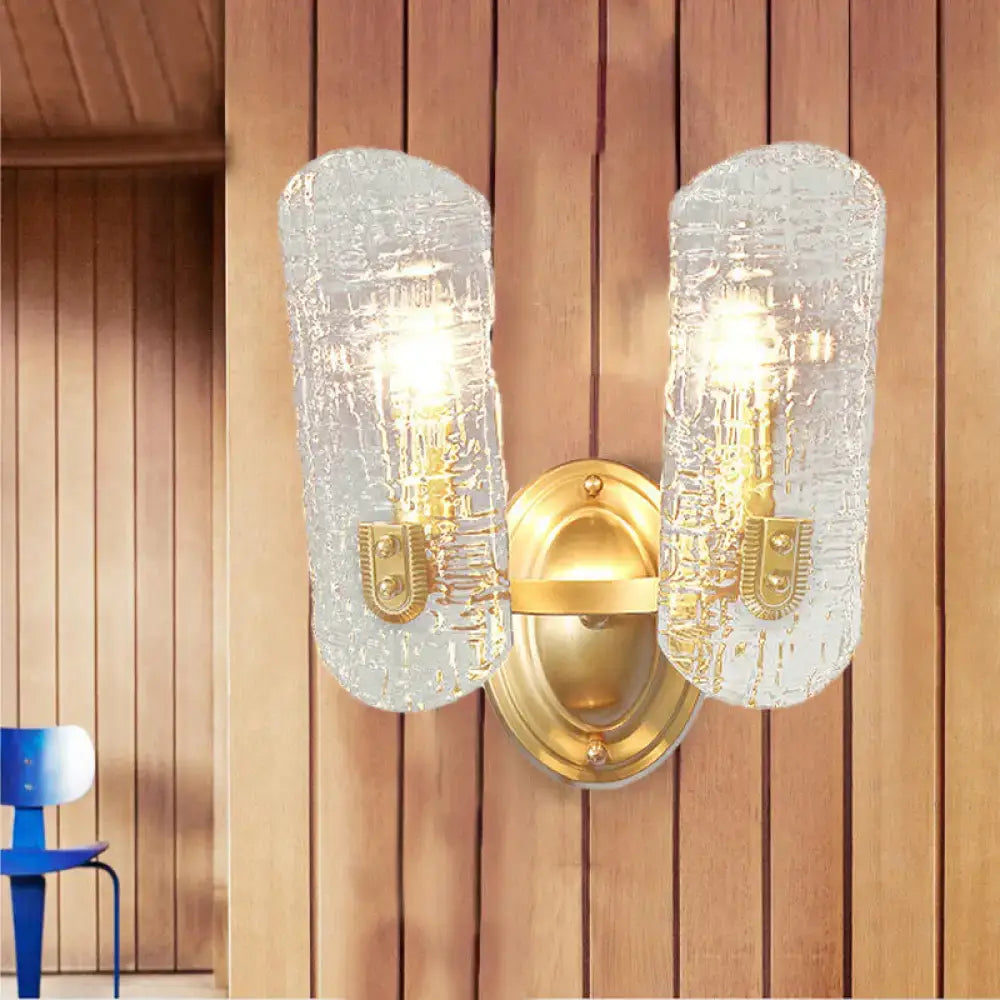 Modern brass sconce with two lights featuring gold-toned clear water glass shades for living room use