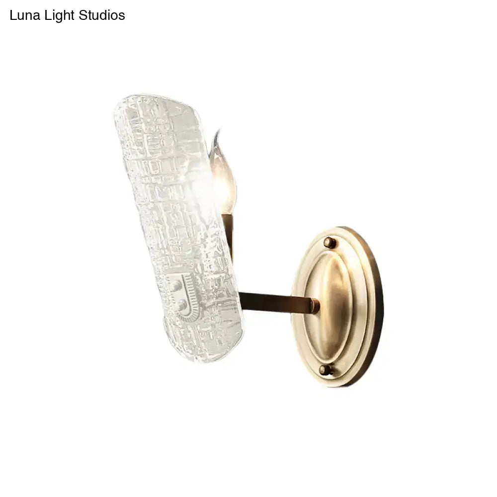 Antique brass wall sconce with two lights and textured clear water glass shade for living room use