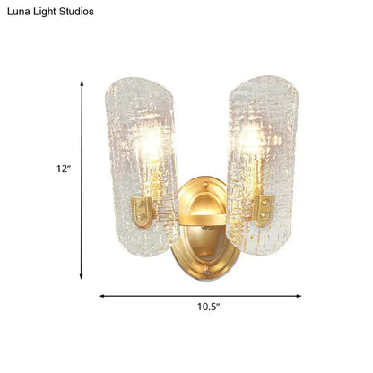 Modern brass sconce with two lights featuring gold-toned metal and clear water glass shades for living room use