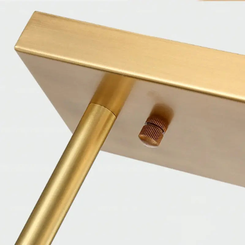 Gold-finished metal table with sleek minimalist design and cylindrical legs paired with frosted glass simplicity globe pendant for dining room