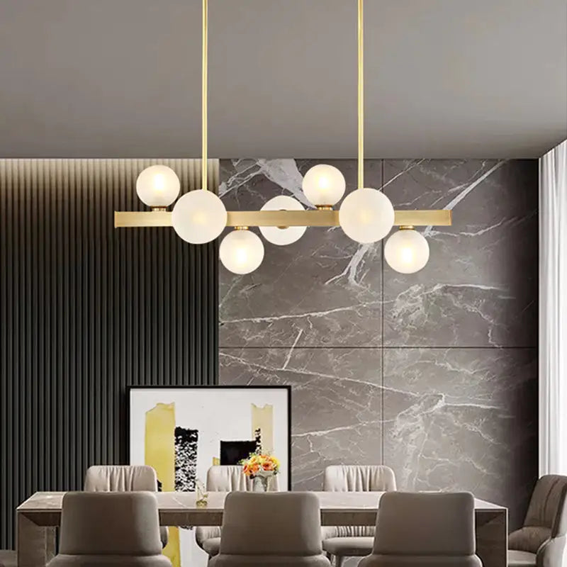 Modern brass simplicity globe pendant featuring gold-toned frame and frosted glass bulbs for dining room lighting