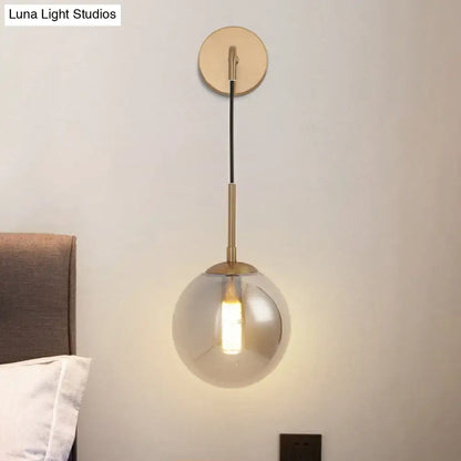 Modern brass smoked glass ball wall hanging lamp with spherical globe and exposed bulb for bedroom lighting