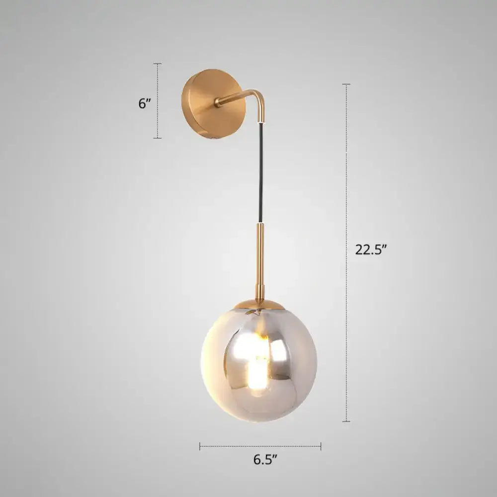 A modern brass smoked glass ball wall hanging lamp with an adjustable arm for bedroom lighting