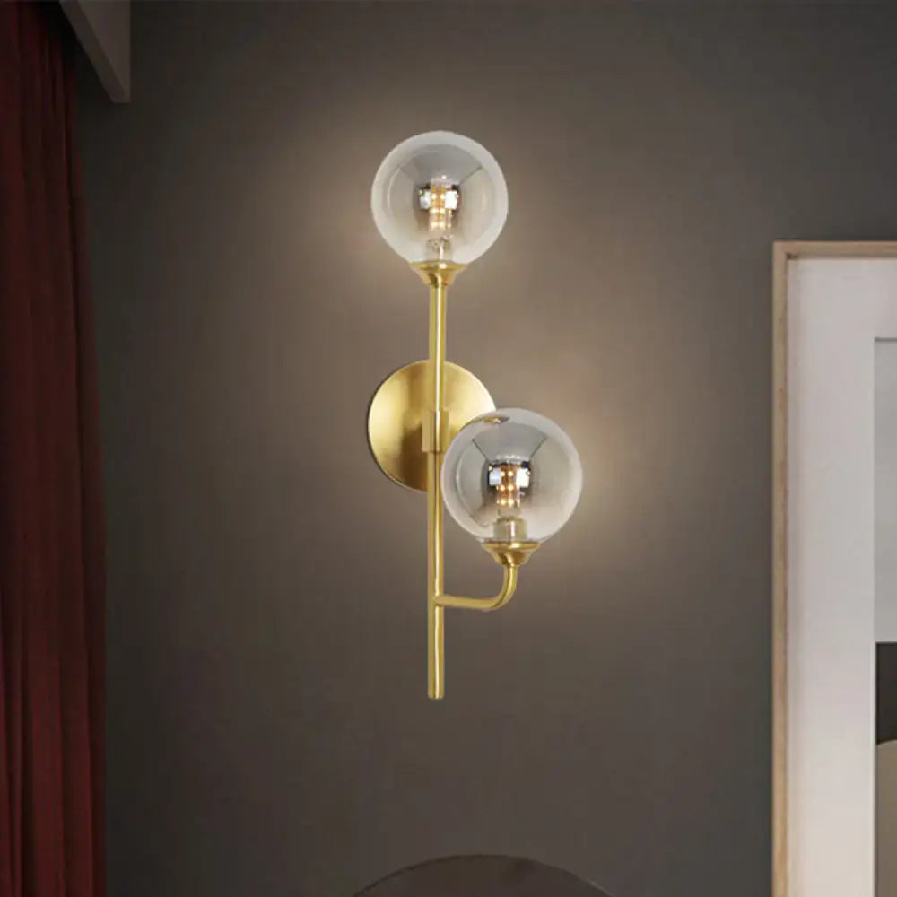 Modern brass sphere wall sconce with amber smoke gray glass globes and exposed filament bulbs for bathroom lighting