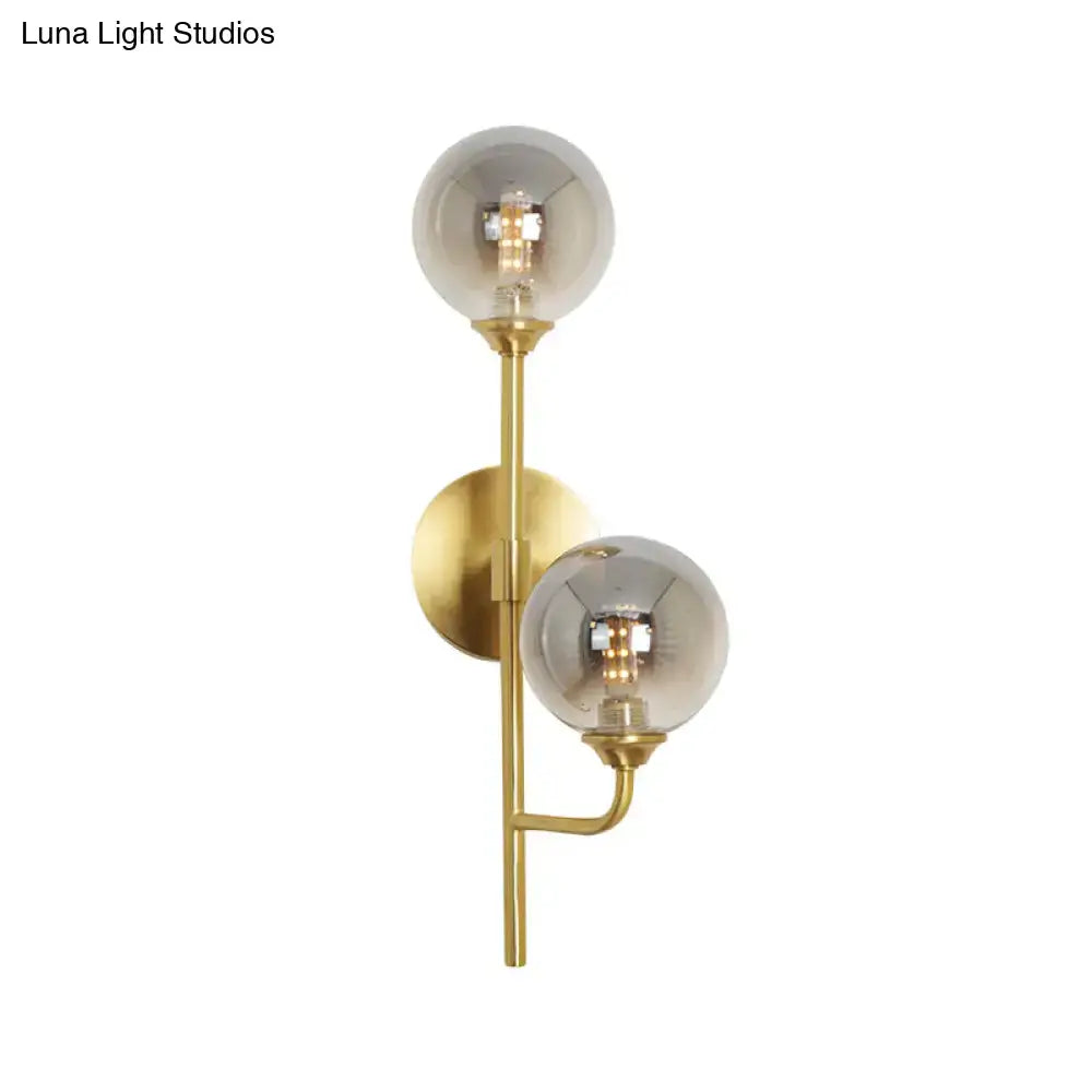 Modern brass sphere wall sconce with amber smoke gray smoked glass globe shades for bathroom lighting