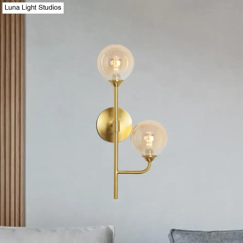 Modern brass sphere wall sconce with amber smoke gray glass globes in a gold-toned minimalist bathroom light design