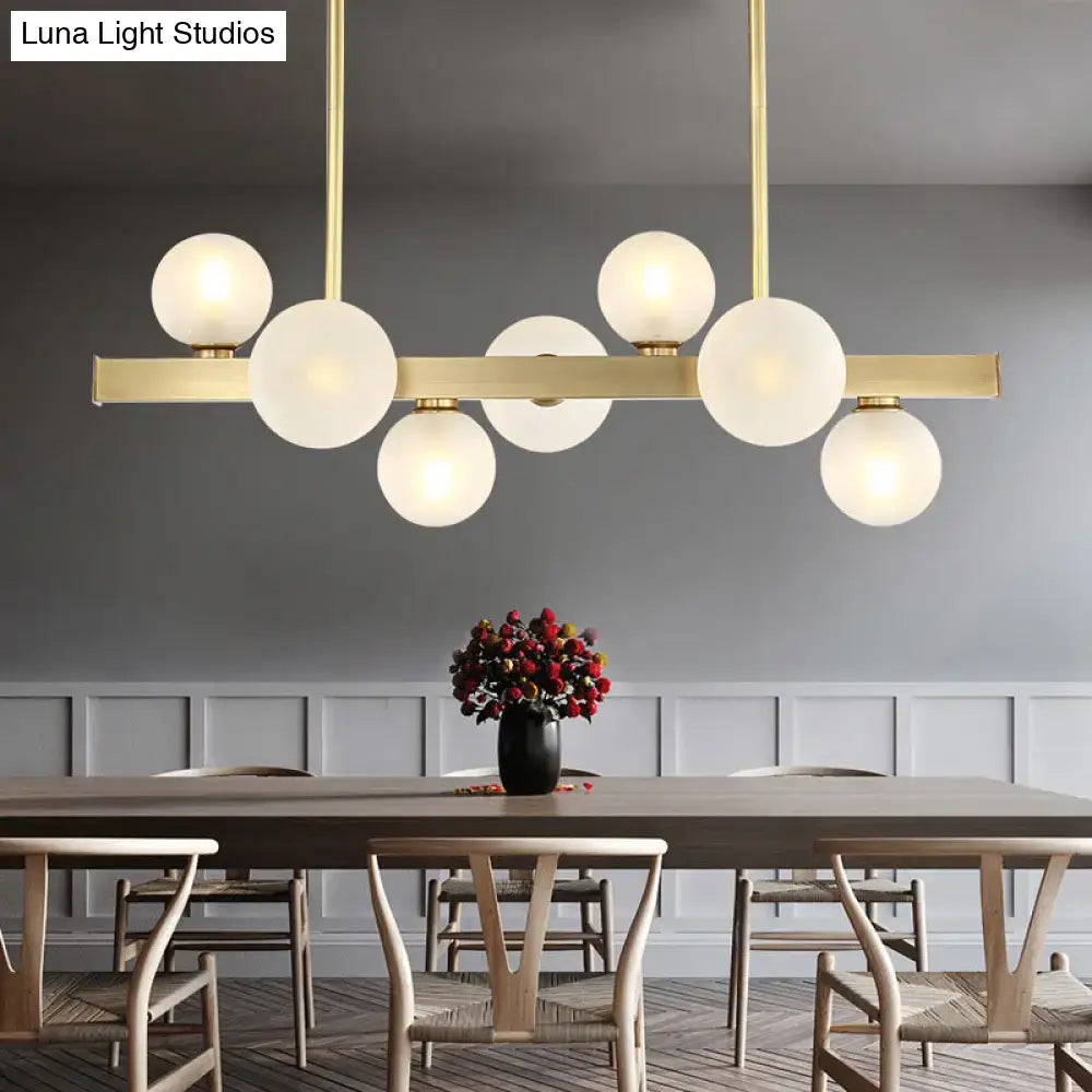 Modern brass spherical glass island ceiling light featuring frosted globe bulb base for kitchen dining use