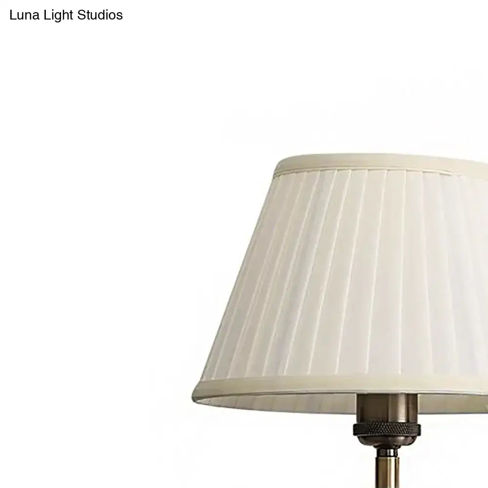 Cream-colored pleated lampshade on modern brass swing arm paper wall mount lamp with metallic base for living room sconce