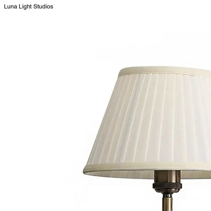 Cream-colored pleated lampshade on modern brass swing arm paper wall mount lamp with metallic base for living room sconce