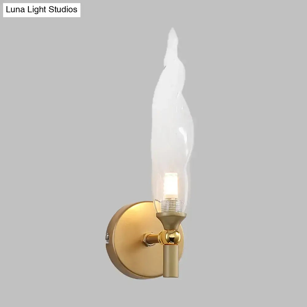 Modern brass torch sconce with gold tone and clear glass flame shaped shade for bedroom wall lighting